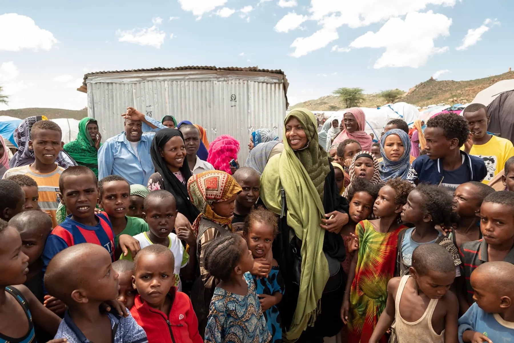 Une intervenante de terrain de LIFE entourée d'enfants et d'habitants dans un camp de déplacés.